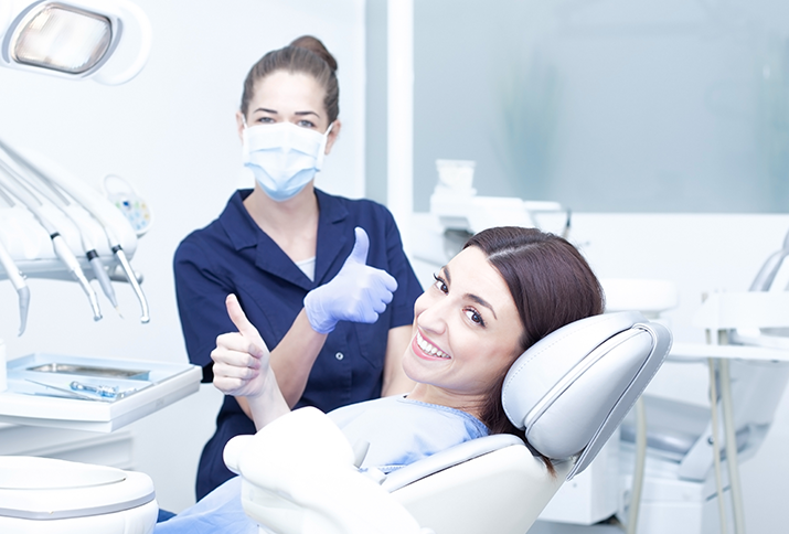 Dentist and patient giving thumbs up in dental clinic