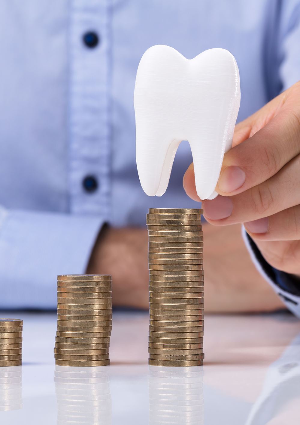 Dental accountant placing model tooth on stack of coins
