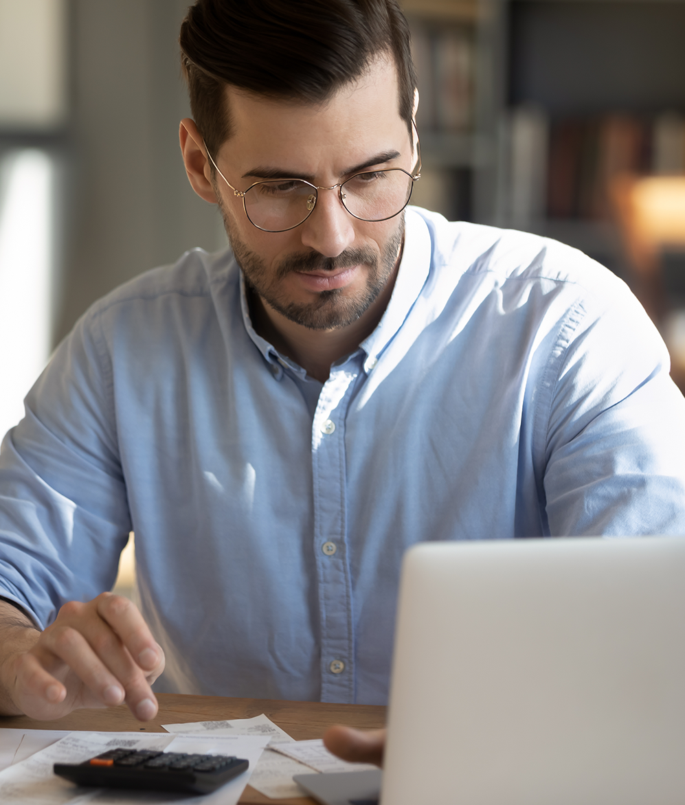 Serious man in glasses planning taxes on laptop
