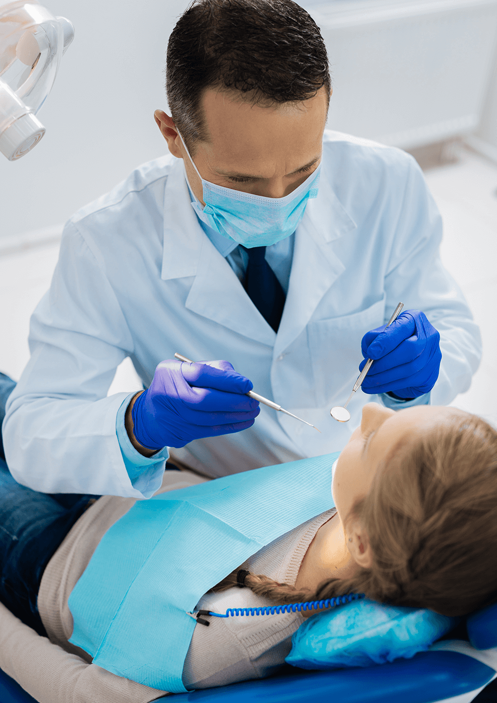 Dentist inspecting seated teenage patient for cavities