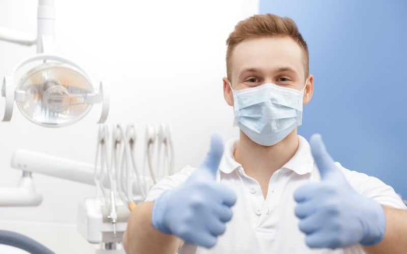 always professional professional dentist wearing protective mask gloves showing thumbs