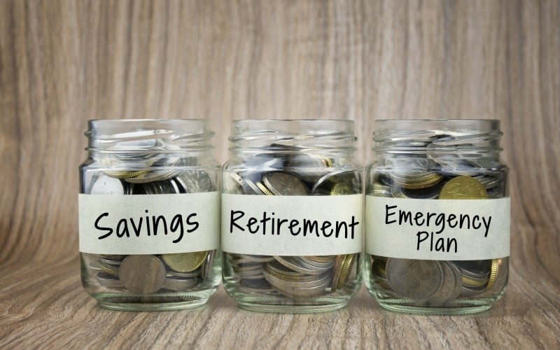 coins in glass jar with saving retirement and emergency plan label financial concept
