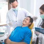 Male dentists treating male patient in dental office