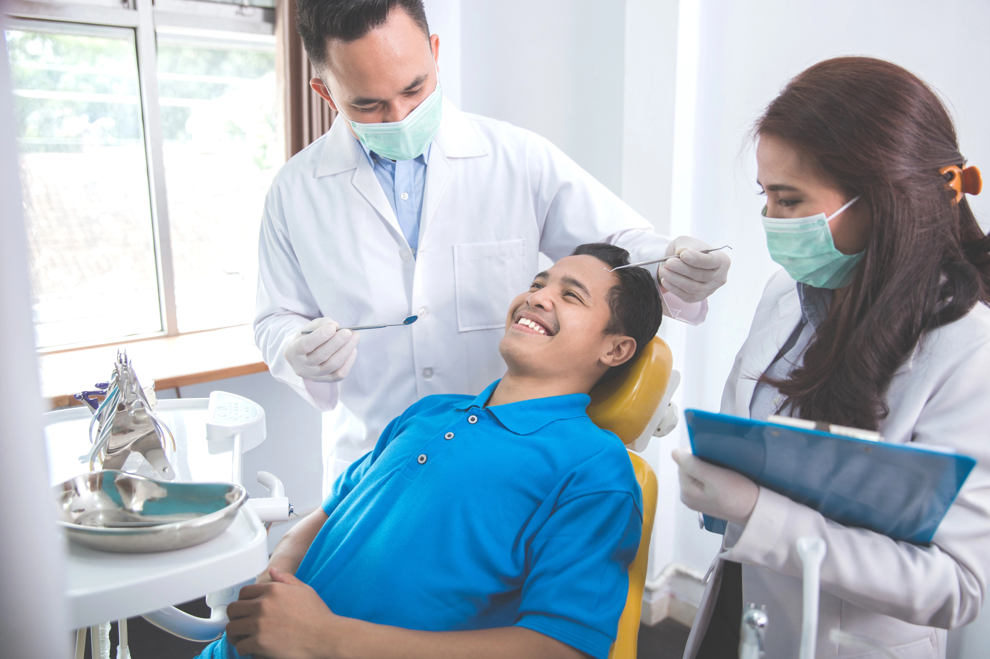 Male dentists treating male patient in dental office
