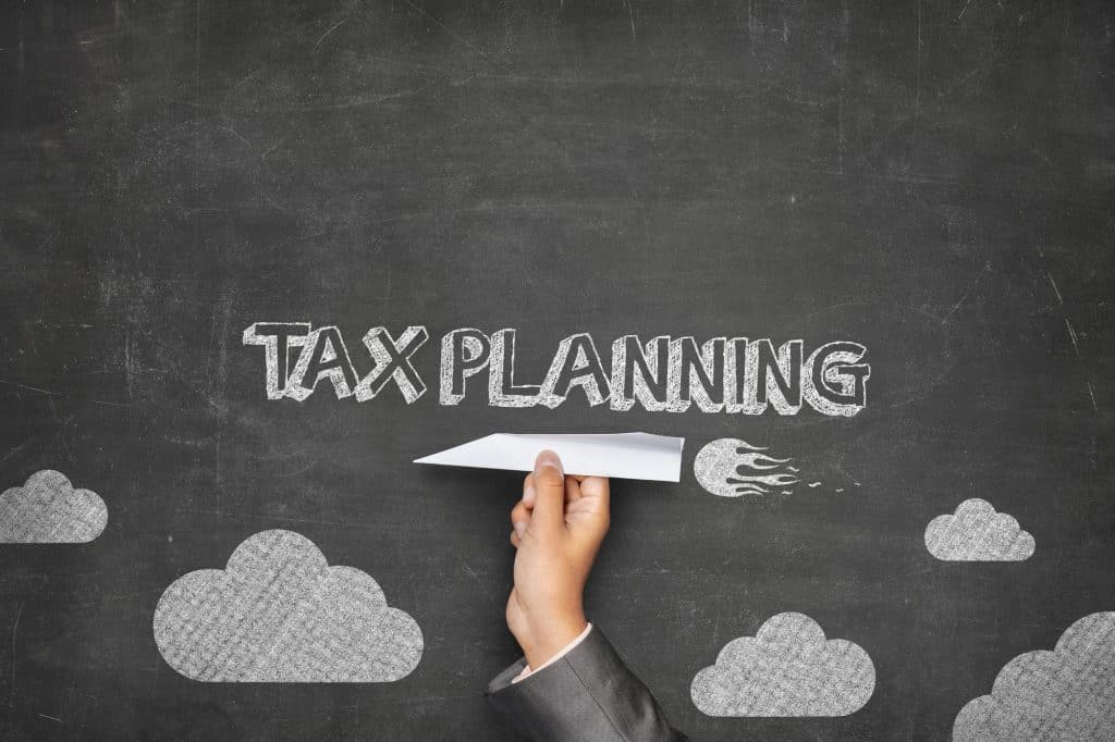 Tax planning concept written on blackboard with paper plane