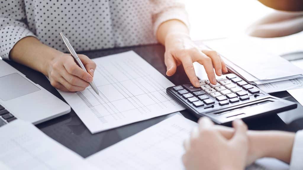 Female accountant using calculator and laptop for tax calculations