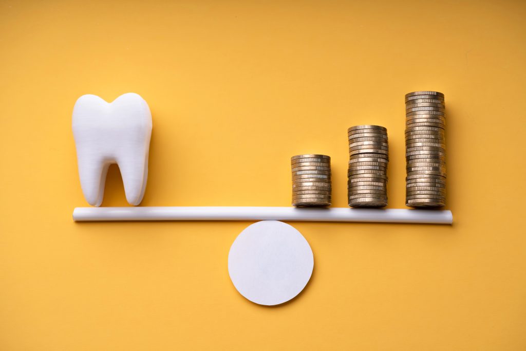 Tooth and stacks of coins representing dental costs