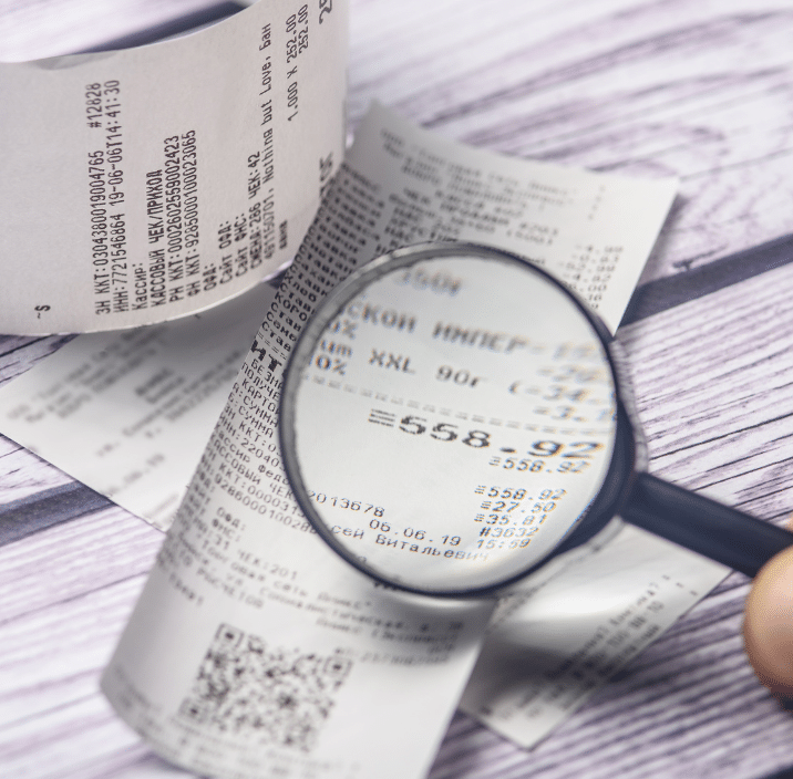 Magnifying glass examining printed receipts - dental tax